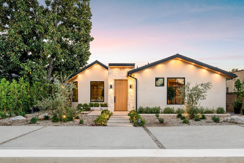 Modern single-story house with a minimalist garden at sunset, featuring clean lines and warm lighting.